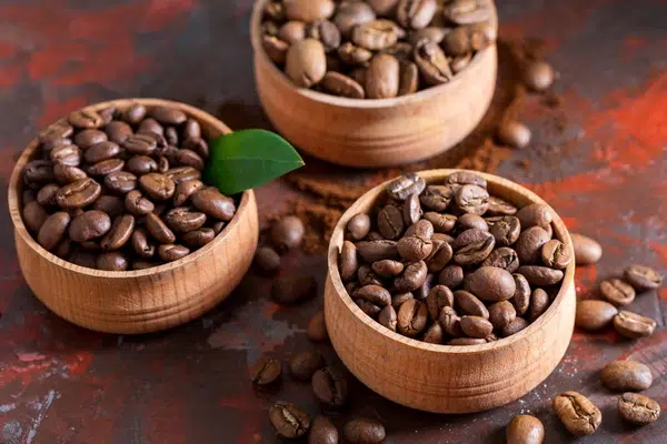 Trois récipients contiennent des grains de café robusta et arabica.